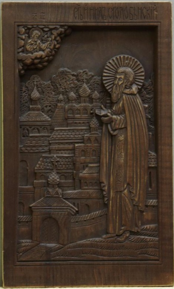 Доска: Икона с двумя врезными шпонками.
На фоне культовых построек с маковками справа изображен святой в монашеских одеждах, вверху слева в облаках Христос.
