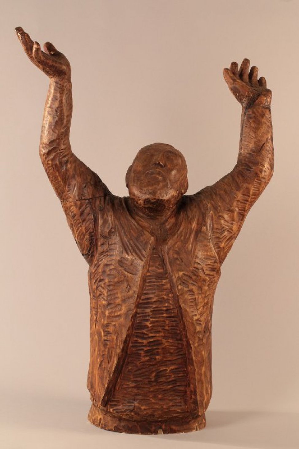Победренное изображение бородатого мужчины с высоко поднятыми руками и раскрытыми вверх ладонями. Голова запрокинута назад и немного повернута вправо. У шеи – ворот рубахи, поверх – жилет, расширяющийся книзу.