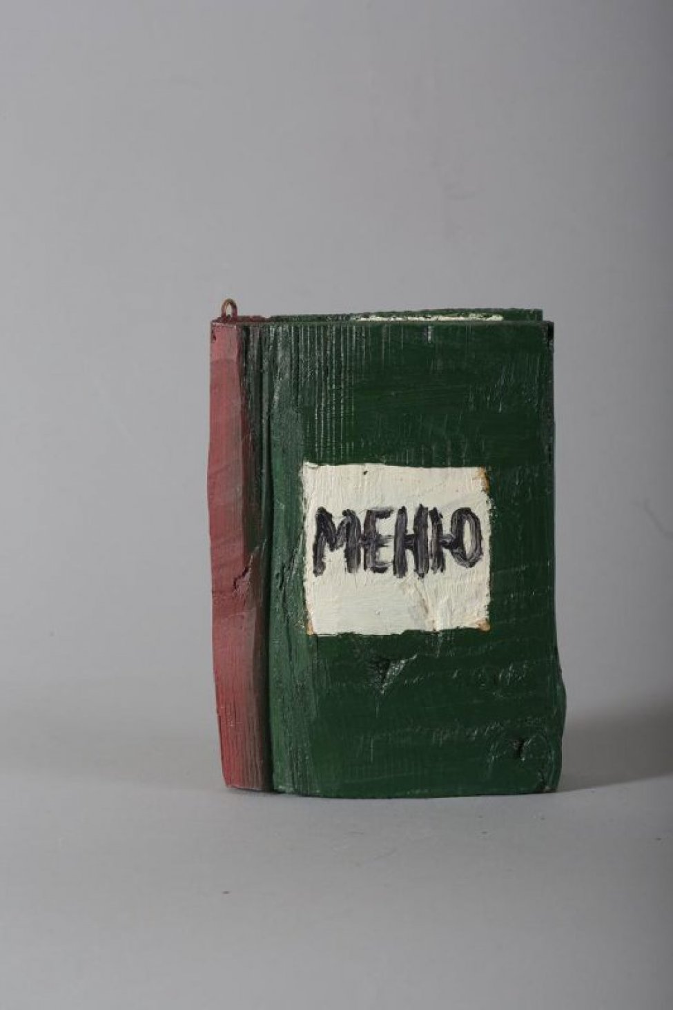 Стилизованное изображение книги темно-зеленого цвета, корешок красно-коричневый. На лицевой стороне белый квадрат с надписью: Меню. Страницы обозначены белым цветом.