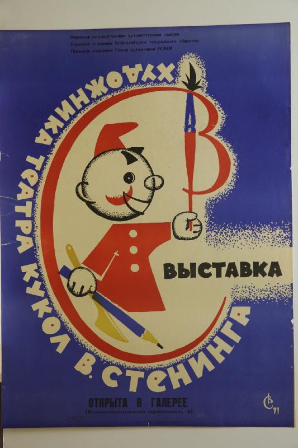На синем фоне - стилизованное изображение палитры и в ней куклы-петрушки в красной рубашке и колпачке с кистью в левой руке, карандашом и стеком в другой руке.