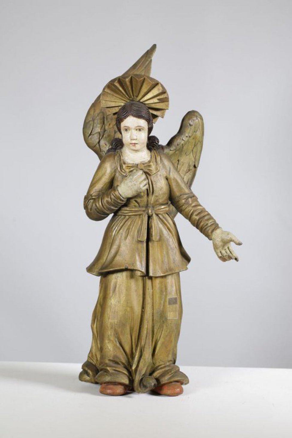 Ангел крайний слева от колонны изображен с протянутыми вперед и влево руками, лицо повернуто вправо; в правой руке держит копье. Ангел в двух позолоченных одеждах. Сзади - два отдельно вырезанных крыла, позолоченных с лицевой стороны, правое крыло поднято вверх, левое - опущено. На голове - позолоченный нимб с рельефно вырезанными лучами.