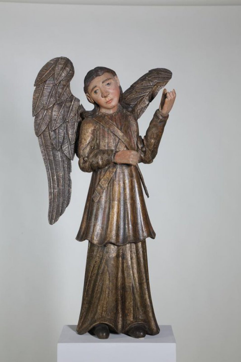 Ангел - парный скульптуре ДС-146, изображен в зеркальной симметрии. На ангеле две одежды золотого цвета. Оба одеяния проработаны крупными вертикальными складками. Крылья посеребрены, их оперение изображено в невысоком рельефе.