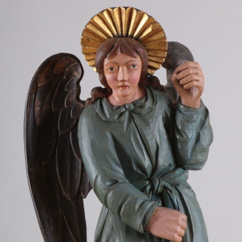 У ангела верхняя одежда синевато-зеленого цвета, нижняя - сиреневого цвета. Сзади находится два отдельно вырезанных позолоченных крыла. Правая рука опущена, а левая - поднята.