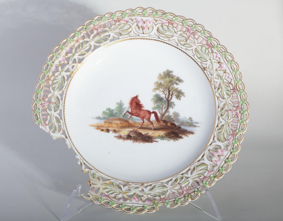Тарелка с прорезным бортом и изображением на зеркале скачущей лошади на фоне пейзажа.