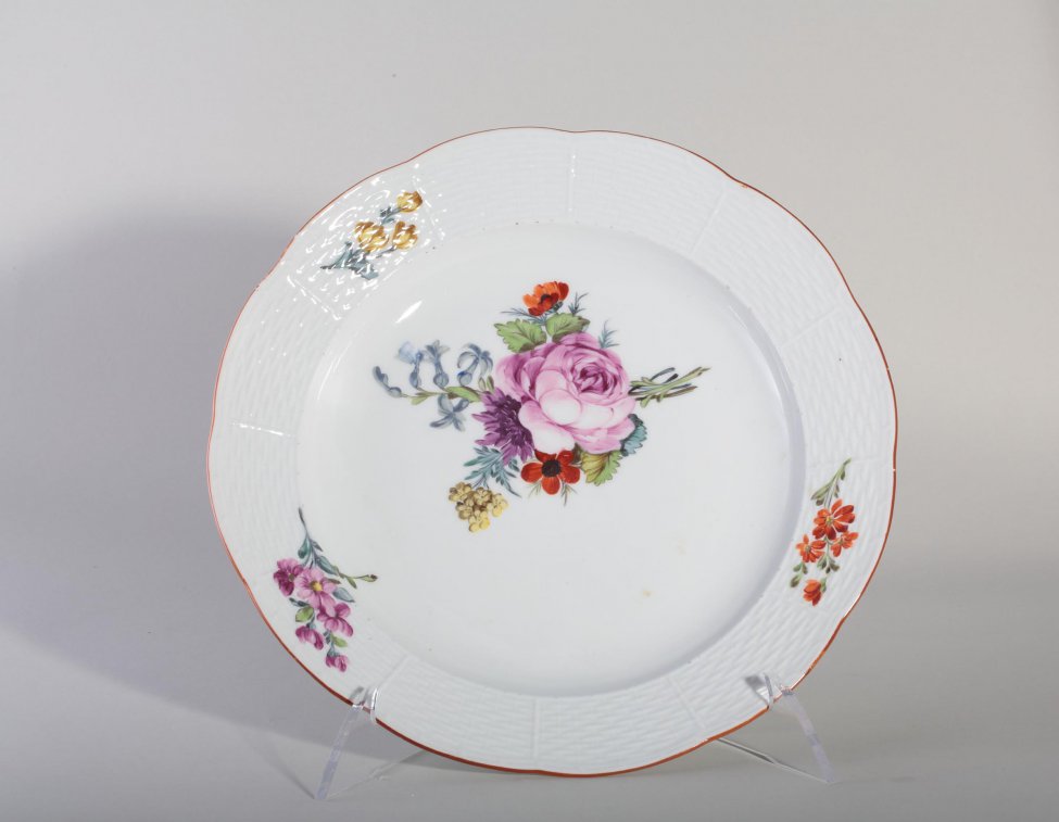 Тарелка мелкая с волнистым коричневым краем; борт декорирован рельефной плетенкой и тремя цветочными ветками; на зеркале - букет цветов с крупной розовой розой