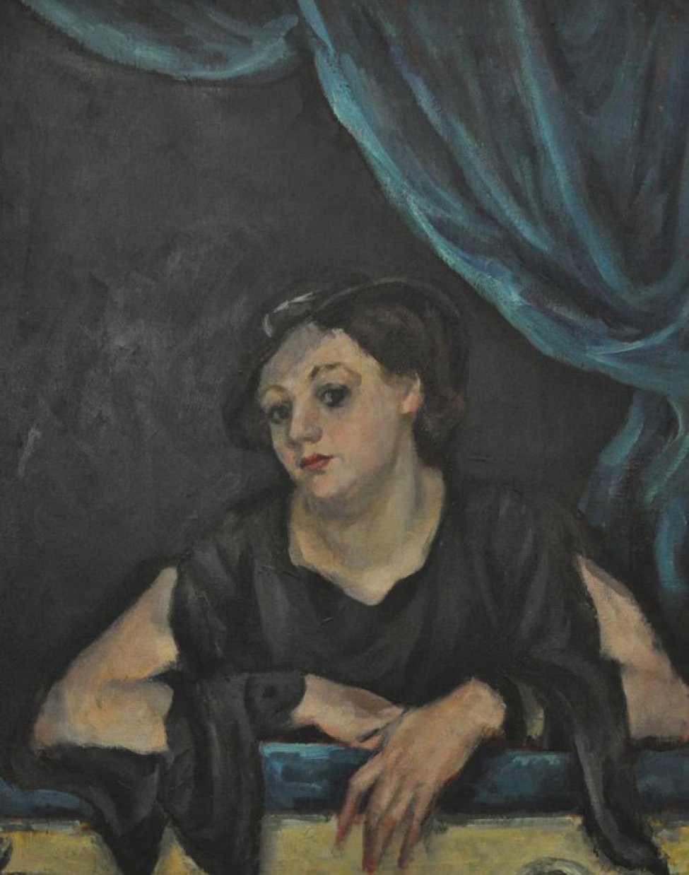 Погрудное изображение молодой темноглазой женщины в шлпяпке, сидящей в ложе. Поворот головы в 3/4 влево. Обнаженные руки положены на голубой бархат барьера ложи. Справа яркая зеленовато-синяя драпировка.