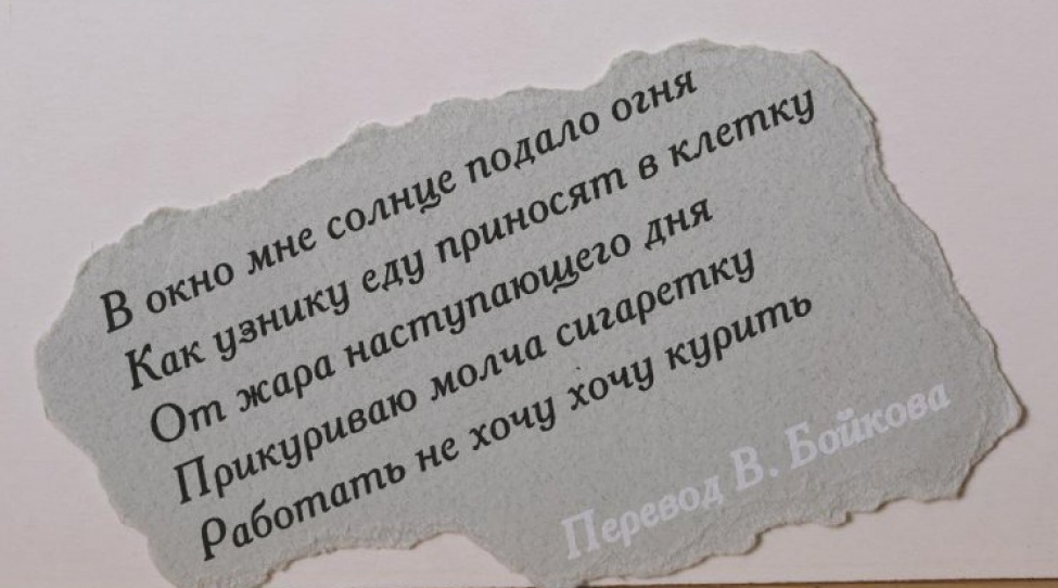 На обрывке серой плотной бумаги текст черной краской в пять строк на русском языке, внизу - фраза "Перевод В. Бойкова" выполнена белым.