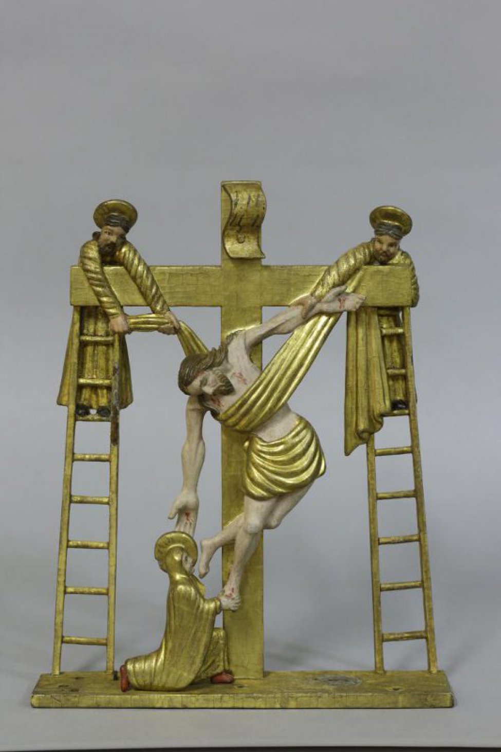 В композиции 7 фигур. Фигура снимаемого с креста Распятого сильно изогнута влево; правая рука повисла; на руках и груди переданы напряженные мускулы; живот впал, на чресленнике позолоченная повязка. Тело Христа повисло на полосе ткани, концы которой поддерживают два апостола, стоящие на верху лестниц, поставленных к перекладинам креста. Внизу креста слева фигура Иоанна Богослова, спрва креста - фигура , склонившейся на правое колено Марии Клеоповой; несколько сзади ее - фигура Богоматери, с повернутой влево головой и со сложенными на груди руками. Крайняя справа фигура Марии Магдалины вырезана с наклоненной вправо головой и со сложенными на животе руками. Апостолы имеют по одной одежде, остальные фигуры по две. На одеждах и ткани частые, мелкие складки. На головах предстоящих нимбы. Крест - 4-х конечный, с изогнутым свитком наверху с установленной надписью. Крест, подставка и одежды (внизу) позолочены.