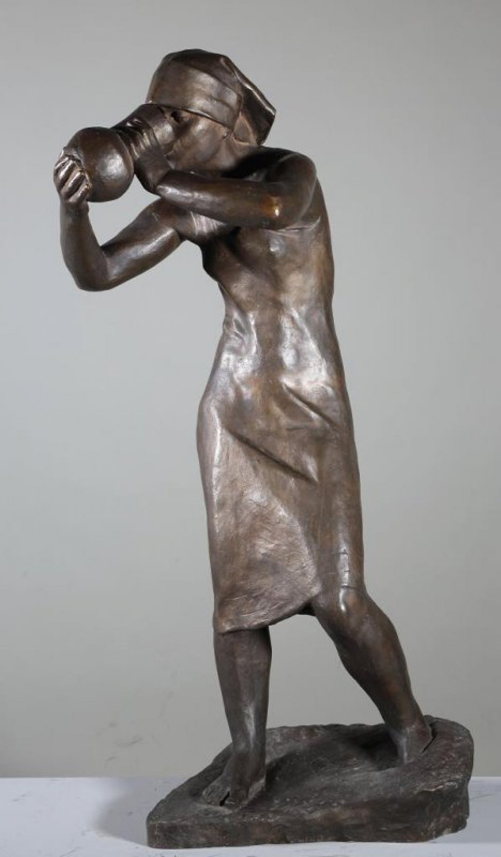 Изображена стоящая девушка в сарафане и платке на голове. Левая нога отставлена в сторону. Обеими руками держит кувшин, поднесенный ко рту.
Обрамление: Постамент неправильной прямоугольной формы.