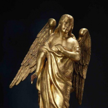 Ангел летящий влево. Левая рука поднята к груди, в правой руке находится чаша. Голова повернута влево. На позолоченных одеждах - большие развивающиеся складки. Отдельно вырезанные два позолоченных крыла  на спине ангела опущены вниз.