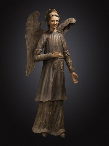 В правой руке ангела - рипида, левая рука опущена. Ангел одет в хитон, поверх которого панцирь, опоясанный поясом. На рукавах выше локтей - бантовые повязки. Сзади на голове - «сияние».