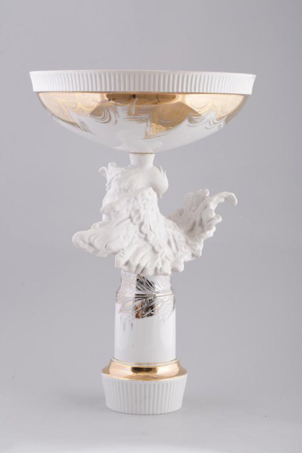 Ваза круглая на высокой ножке со скульптурной фигурой белого голубя с распущенными крыльями и хвостом; верхняя часть вазы декорирована золоченым растительным орнаментом.