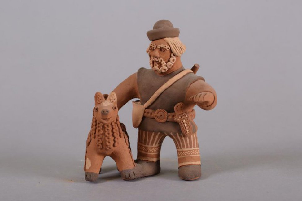 Стилизованная композиция, изображающая охотника с ружьем, сумкой через плечо, кинжалом на ремне; справа от него - собака
