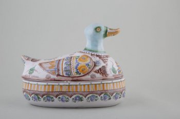 В форме утки со съёмной крышкой; расписана геометрическим и цветочным орнаментом; на грудке изображен домик с дымящей трубой