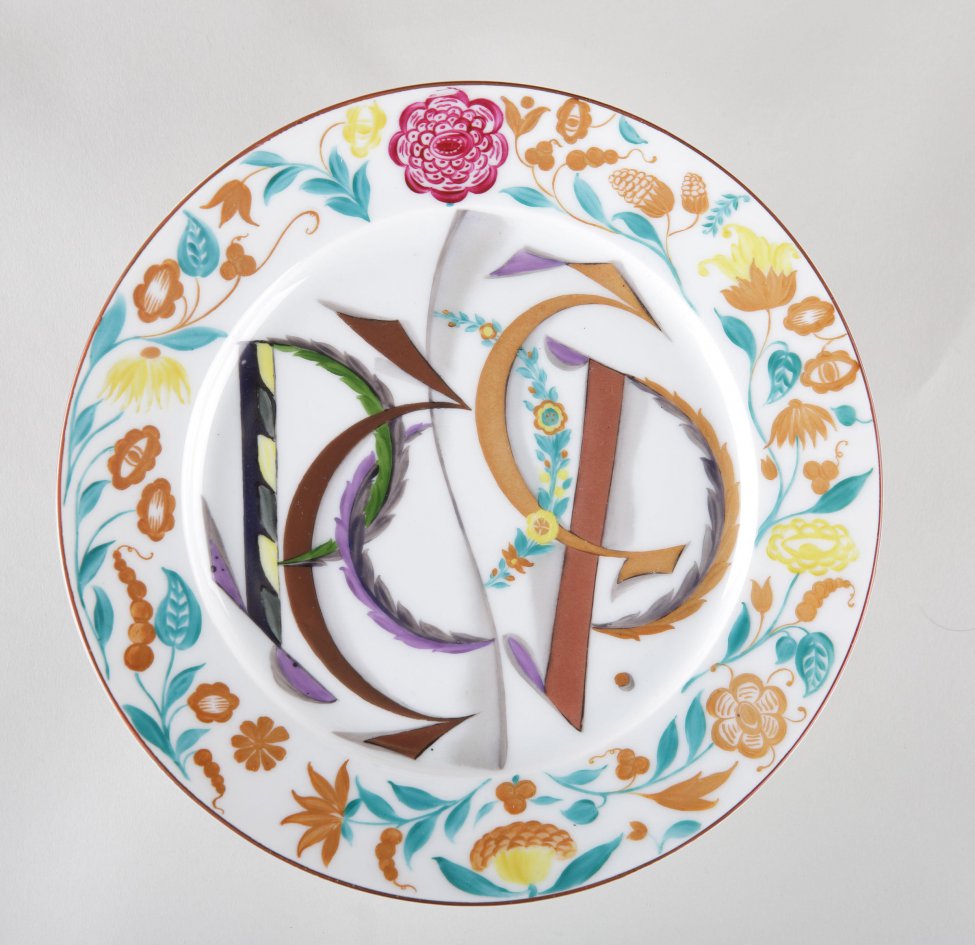 Тарелка с росписью на дне цветными буквами: "РСФСР". Кругом по борту роспись цветочной орнаментацией. Край тарелки коричневый.