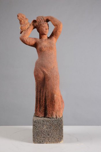 Изображена женская фигура в облегающей одежде с вертикальными складками ниже бедра. Левая нога полусогнута в колене и выдвинута вперед. Руки подняты над головой и поддерживают волнистые волосы. На согнутой правой руке, на запястье - птица. Скульптура на кубическом постаменте.