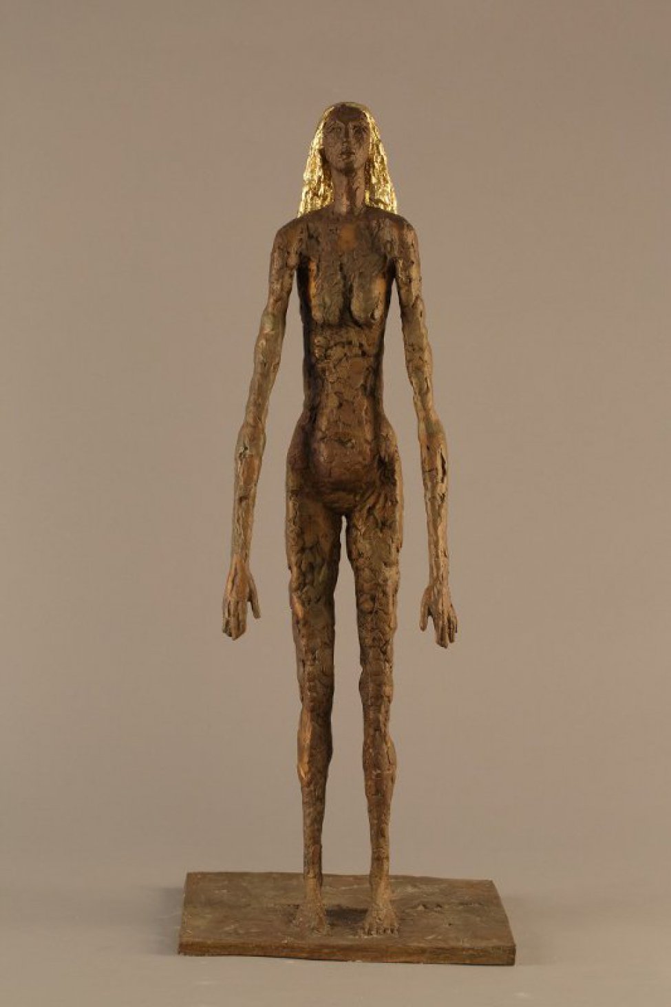 На прямоугольном основании изображена в полный рост стилизованная фигура обнаженной женщины с золотистыми волосами до плеч. Руки опущены и слегка вытянуты вперед, голова слегка поднята вверх. Поверхность скульптуры фактурная, имитирующая лепку из пластилина.
