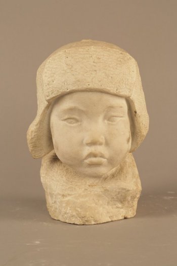 Изображена голова мальчика в зимней шапке-ушанке. Раскосые глаза, пухлые щеки, курносый нос, толстые губы плотно сжаты.