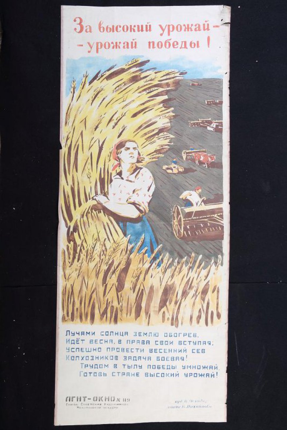 Изображено: женщина со снопом в руке, за ней на поле работают сельскохозяйственные машины.