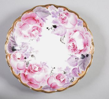 Круглая с приподнятым волнистым краем; по борту роспись в виде крупных розовых роз; по краю широкая золоченая полоса.