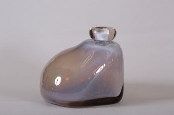 ваза из матового серого стекла, неправильной, вытянутой кверху формы, с широким основанием и узкой горловиной.