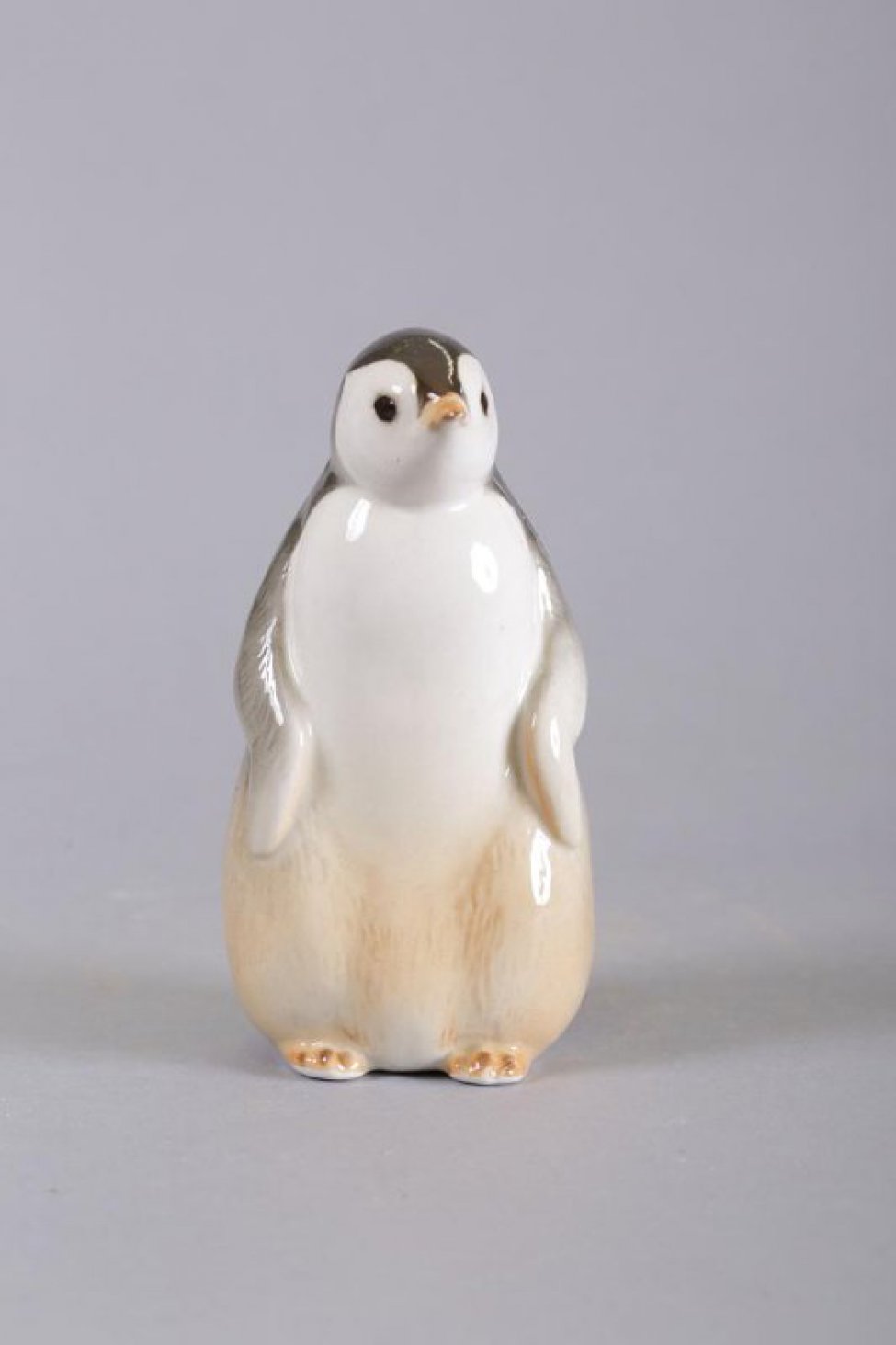 Стилизованное изображение фигуры стоящего на лапах пингвина, крылья опущены вдоль туловища; голова в правом развороте; маленький хвост в форме треугольника.