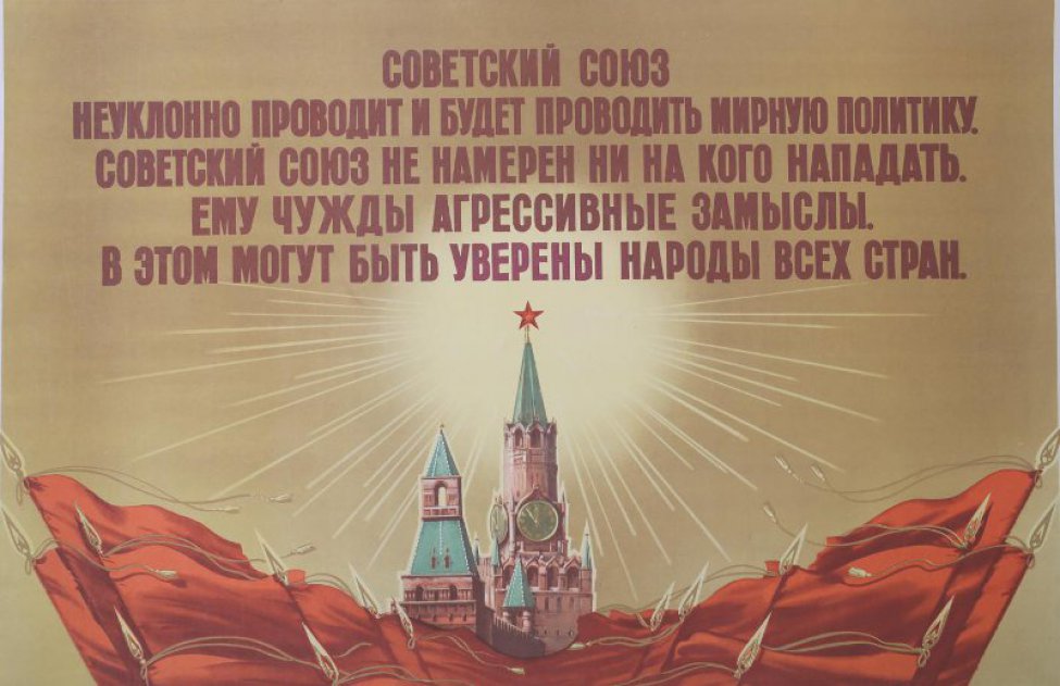 Изображено: Кремлевская башня,озаренная лучами солнца. Ниже красные знамена. Наверху текст.