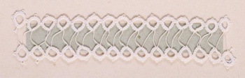 Образец белого цвета в виде двух узких полосок мелких колец соединенных между собой тонкой нитью. Образец пришит к картонному листу.
