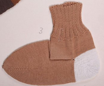 Носок светло-коричневого цвета с белой пяткой. верхняя часть носка связана в технике 