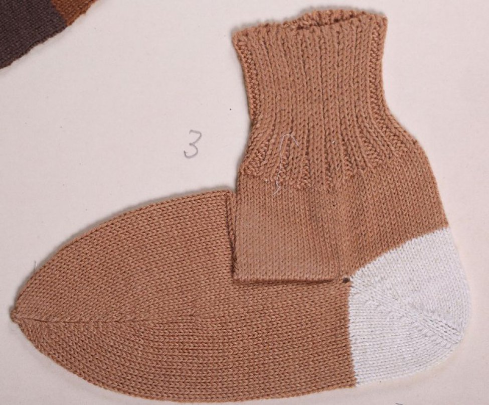Носок светло-коричневого цвета с белой пяткой. верхняя часть носка связана в технике "резинка"