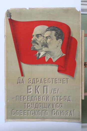 Изображен вверху на красном знамени портреты тт.Ленина и Сталина. Внизу текст: 