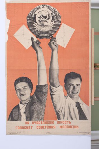 Изображены две фигуры: юноша и девушка с поднятыми руками, в которых держат по конверту. Над ними герб СССР.