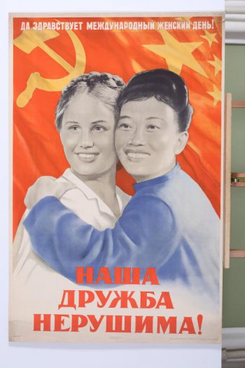 Изображена китайская женщина в синей одежде, обнимающая русскую женщину в белой кофте. Наверху текст: 