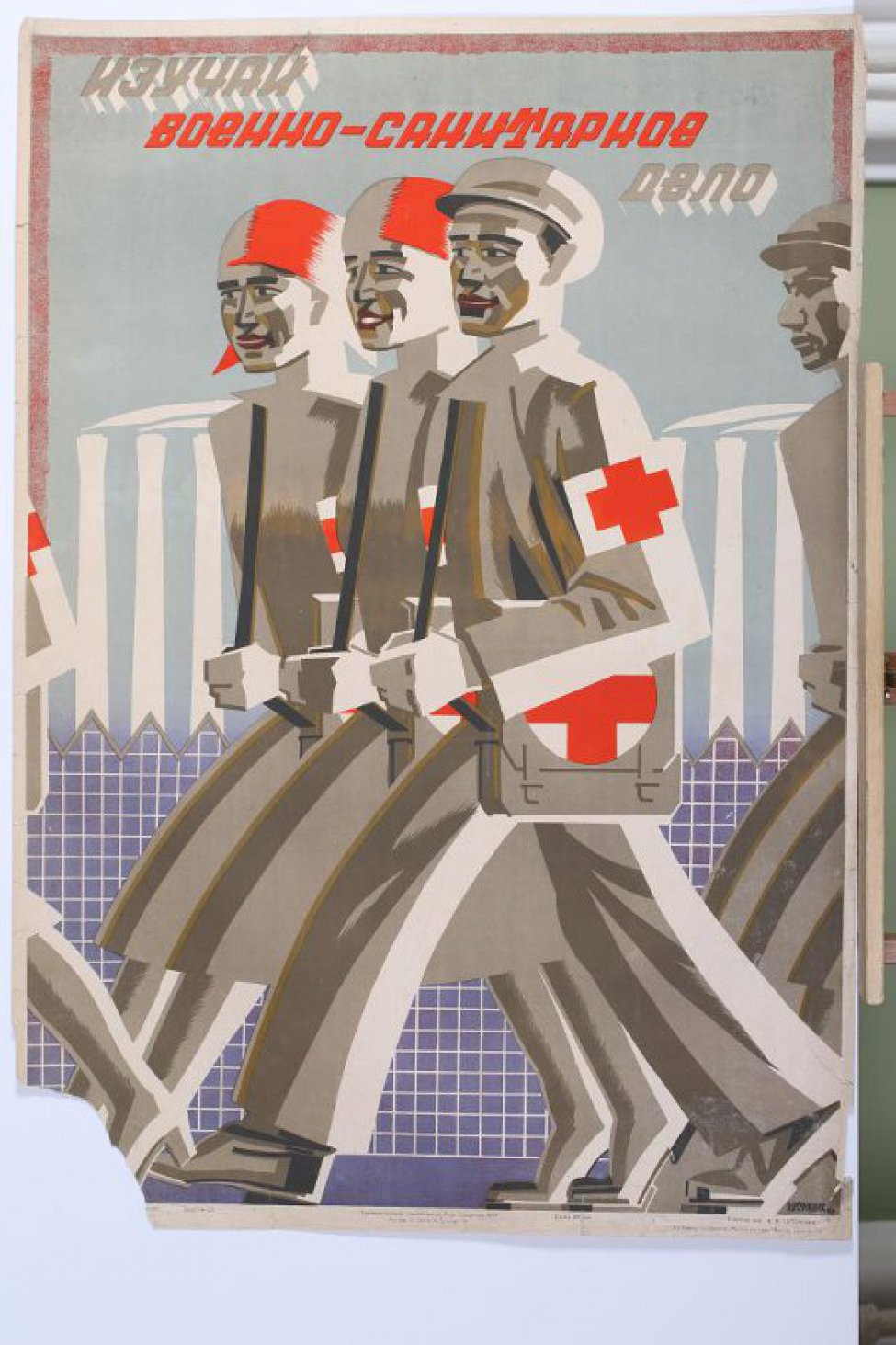 Изображены две девушки и юноша с повязками красного креста на рукавах и сумками первой помощи. На втором плане силуэты, фабричных строений.