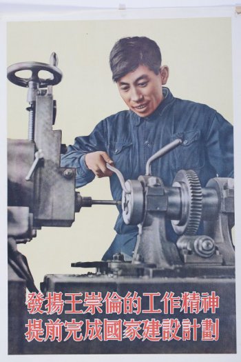 Изображен молодой рабочий в синей рубашке. Он стоит у станка для резания металла. В правой руке у него инструмент, которым он направляет станок.
