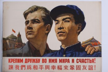 Изображено погрудно русский и китаец. Их взгляды устремлены вправо. Справа от них видны здания Кремля, слева- китайский дом. Под изображением текст на русском и китайском языке.