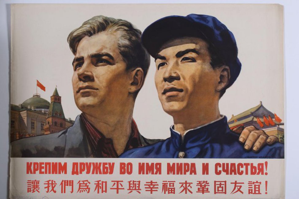 Изображены два молодых мужчины: русский и китаец. Слева от них башни московского кремля; справа крыша китайского дома, украшенная красными флагами. Под изображением:         " Крепим дружбу во имя мира и счастья!" Ниже текст из пятнадцати иероглифов.