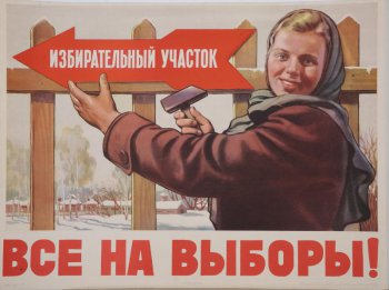 Изображена повернувшись к зрителю , молодая девушка в платке, она прибивает к забору красную стрелку с надписью