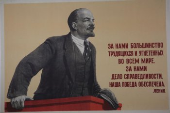 Изображено: В.И.Ленин  стоит на трибуне, в правой руке держит кепку. Справа текст: