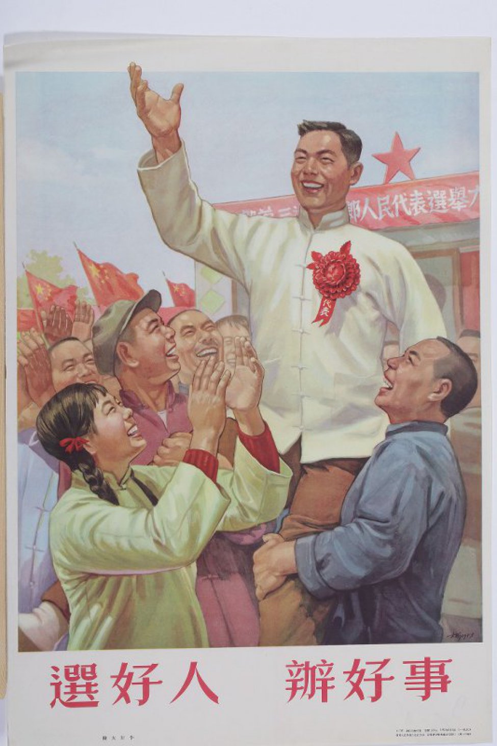 Изображена группа улыбающихся китайских мужчин и девушка, они подняли на руки мужчину с красным цветком и ленточкой на груди. Под плакатом текст из шести иероглифов.