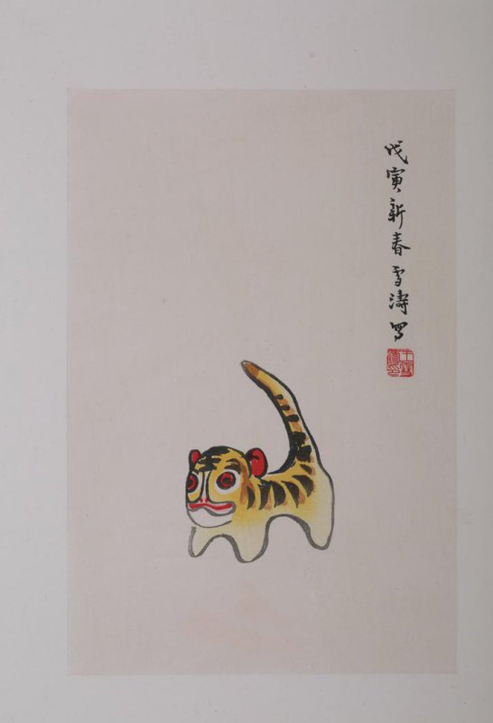 Изображен тигр, стоящий на тупых коротких лапах с поднятым вверх хвостом. Голова круглая,с  красными глазами и ушами. Вверху справа 8 иероглифов.