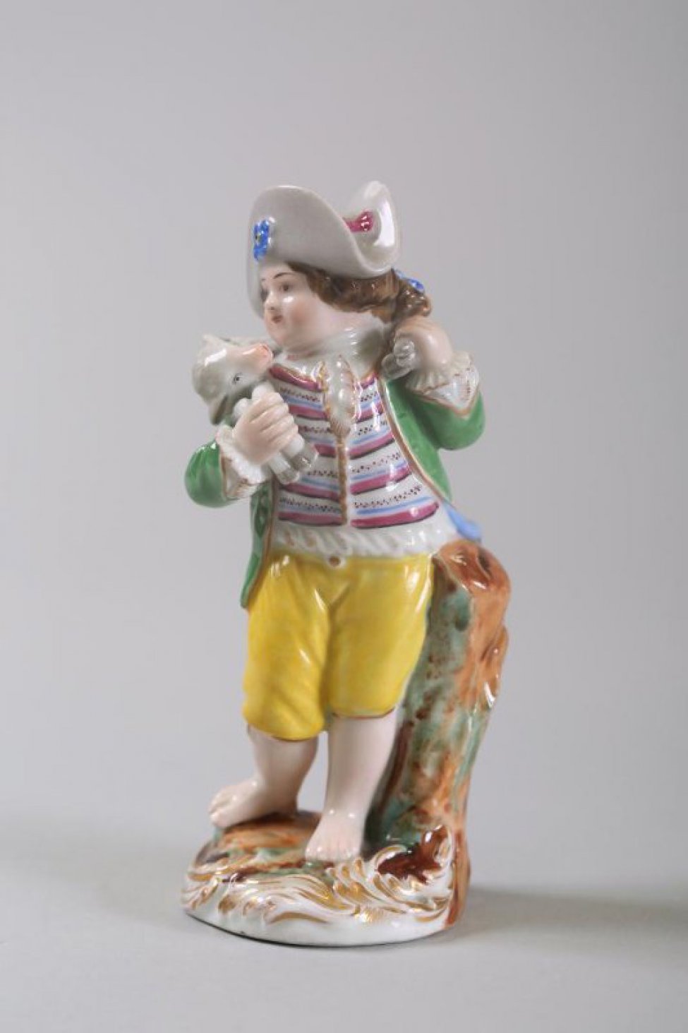 На круглом постаменте изображен мальчик в коричневом камзоле, серой шляпе, босой. Он несет на плечах барашка, держа его за ноги. На постаменте рельефная, голубая с позолотой, орнаментация.