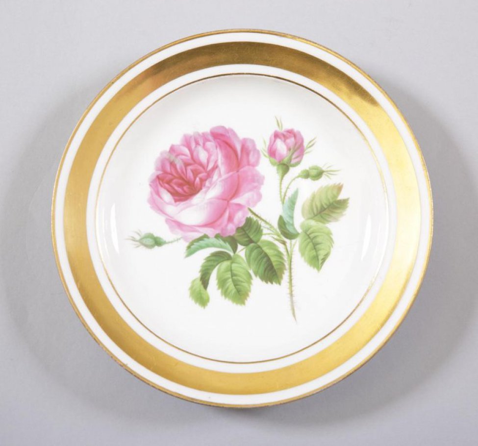 Тарелка белая, по борту три золотые каймы, средняя из них - широкая. На зеркале изображена красная роза с бутоном и листьями.