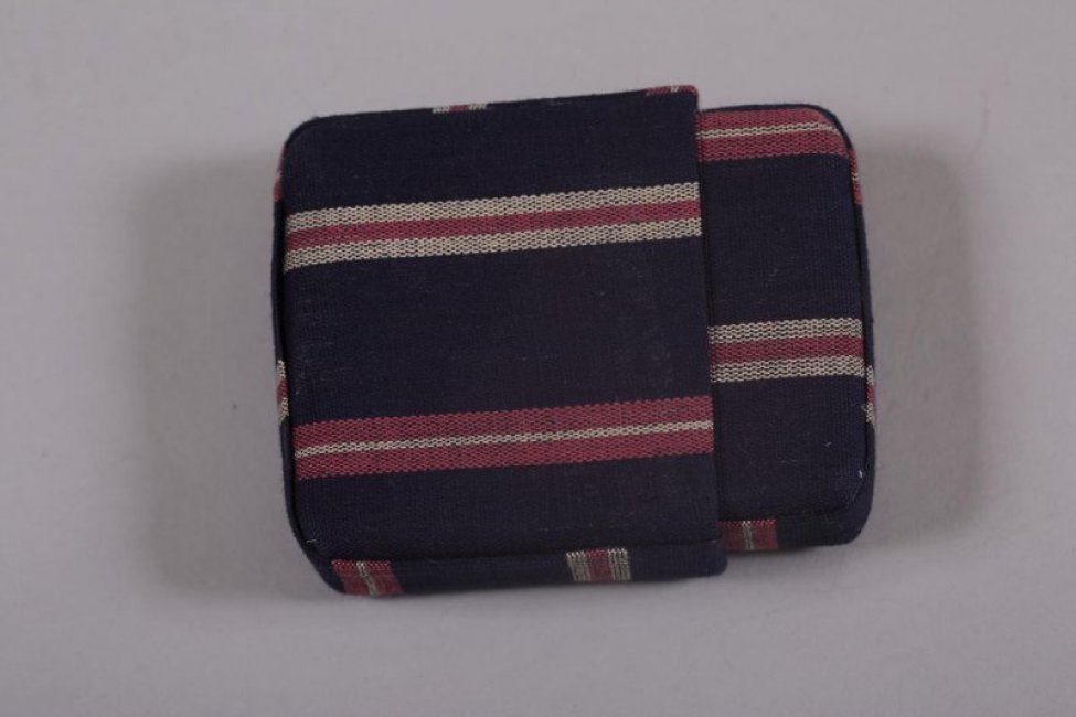 Четырехугольный со срезанным краем, съемной выдвижной крышкой, из хлопчатобумажной синей ткани с узором из белых и красных полос.