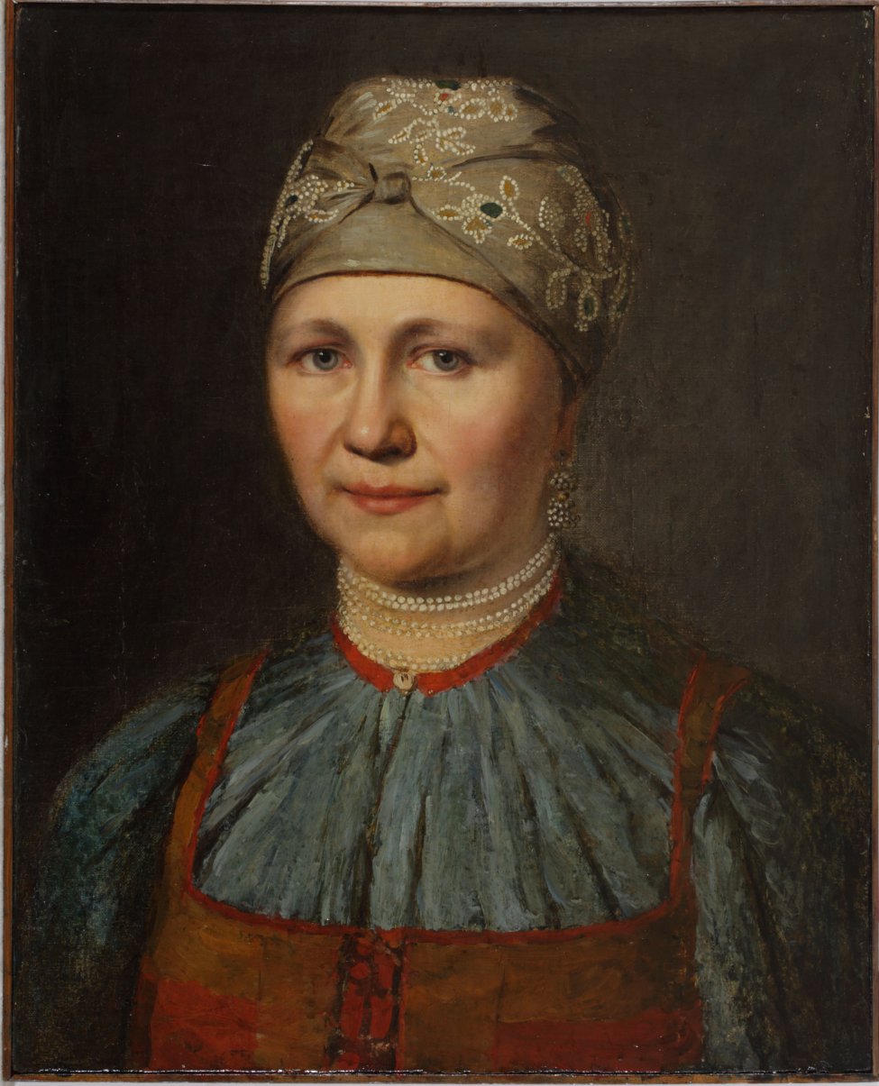 Изображена женщина с серыми глазами, обращенными на зрителя, с повязкой на голове, шитой узорами, с шестью нитками бус на шее, в синей кофте и красном сарафане. 