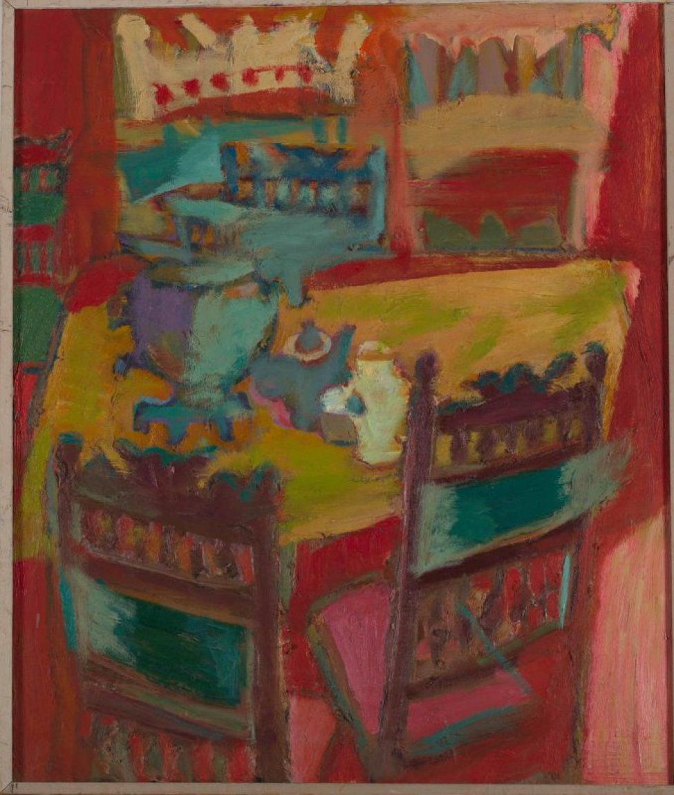 На красном фоне изображен фрагмент интерьера со столом и стульями. На желто-зеленой поверхности стола самовар и два чайника. К столу придвинуты стулья с резными спинками и розовыми сиденьями, которые видно на первом плане.