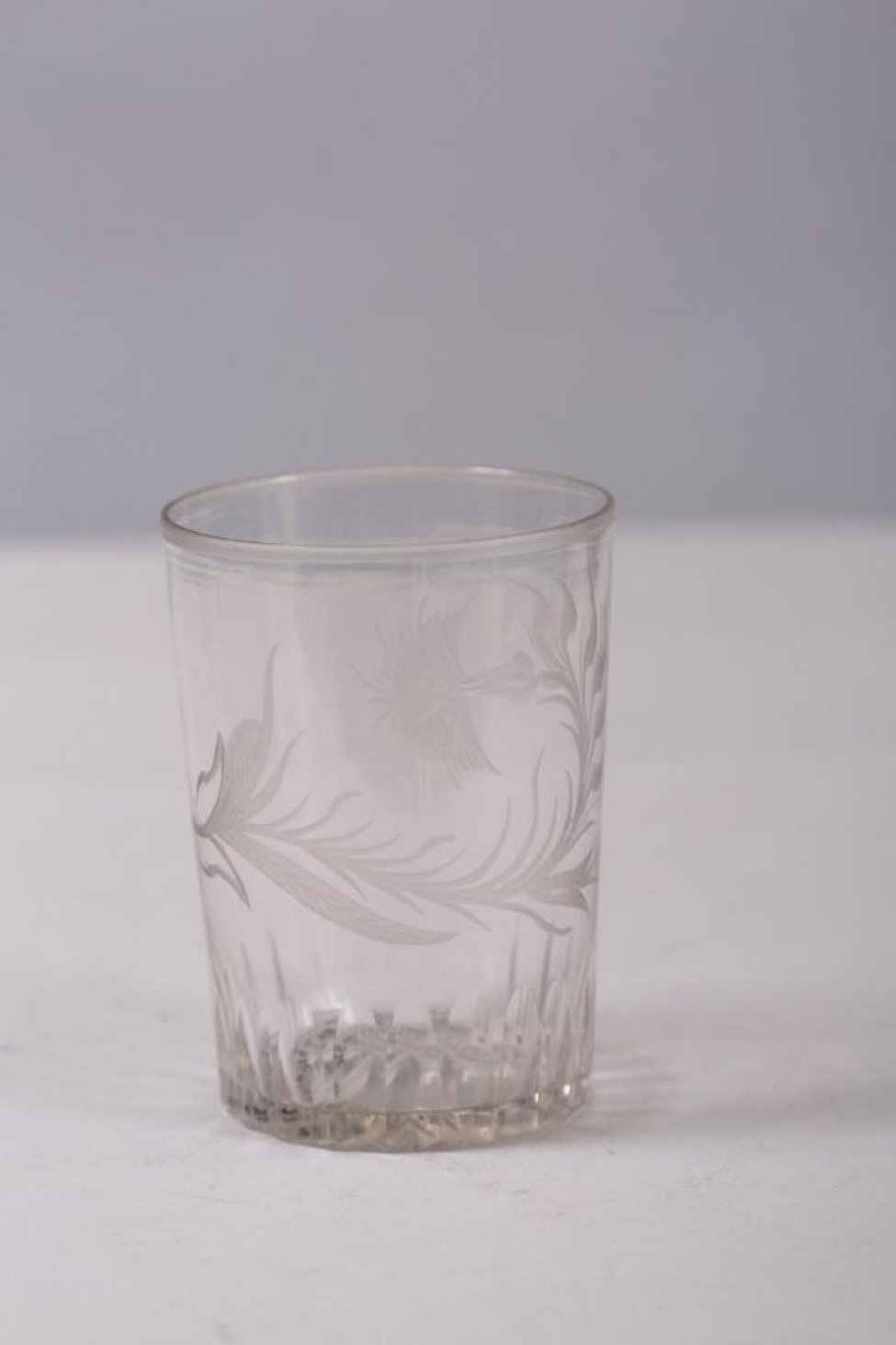 Стакан цилиндрической формы. Нижняя часть тулова  стакана с вертикальными гранями. На тулове с одной стороны изображена резная гвоздика с листочками. По краю борта стакана матовая резная полоска.