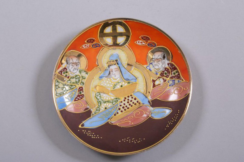 Блюдце мелкое, на низкой кольцевой ножке. На зеркале и по борту - композиция из трех фигур (двух мужчин и одной женщины в центре), одетых в "восточные" одежды. Фон в верху - оранжевый, в низу - коричневый.