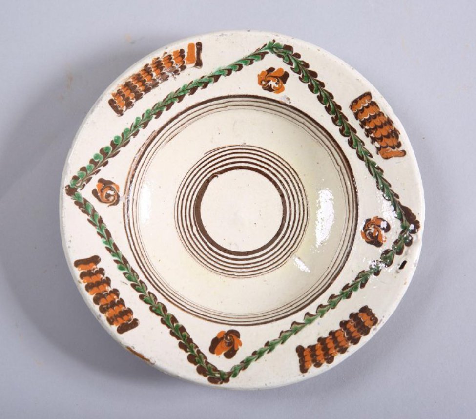 Тарелка серовато-белая, орнаментирована с лицевой стороны. В центре - коричневые круги. Обратная сторона тарелки без глазури.
