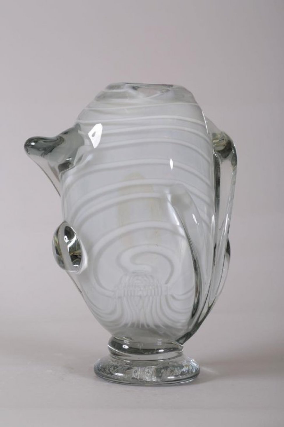 ваза серого цвета с белыми полосами из толстого стекла, вертикальной, не правильной формы, с налепами на ножке, с узким отверстием. Налепы и ножка из прозрачного стекла.